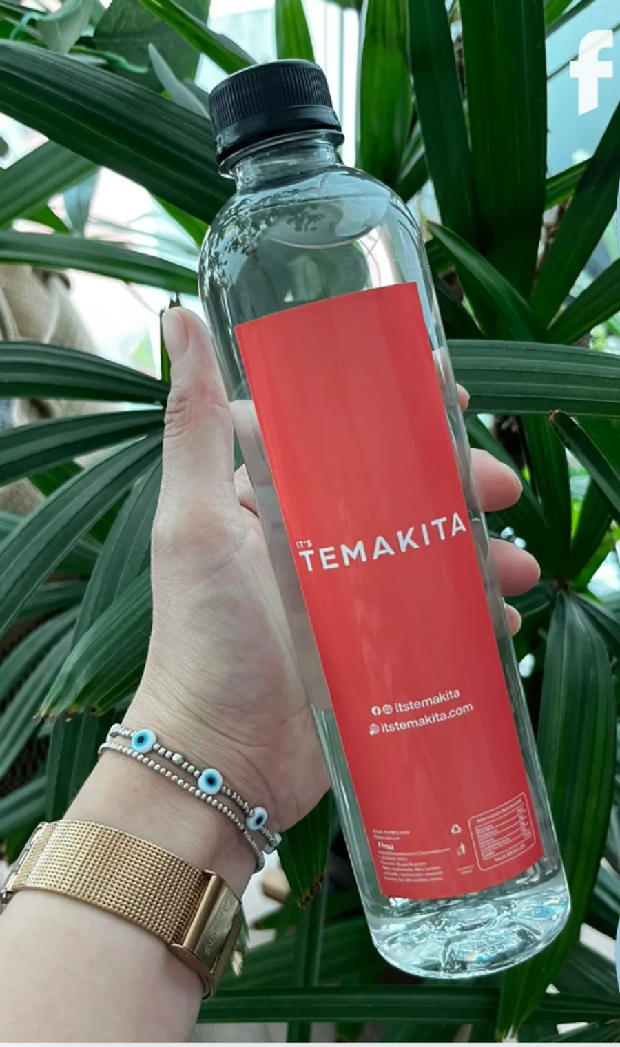 Mano sosteniendo una botella de 500 ml con etiqueta coral de un restaurante japonés